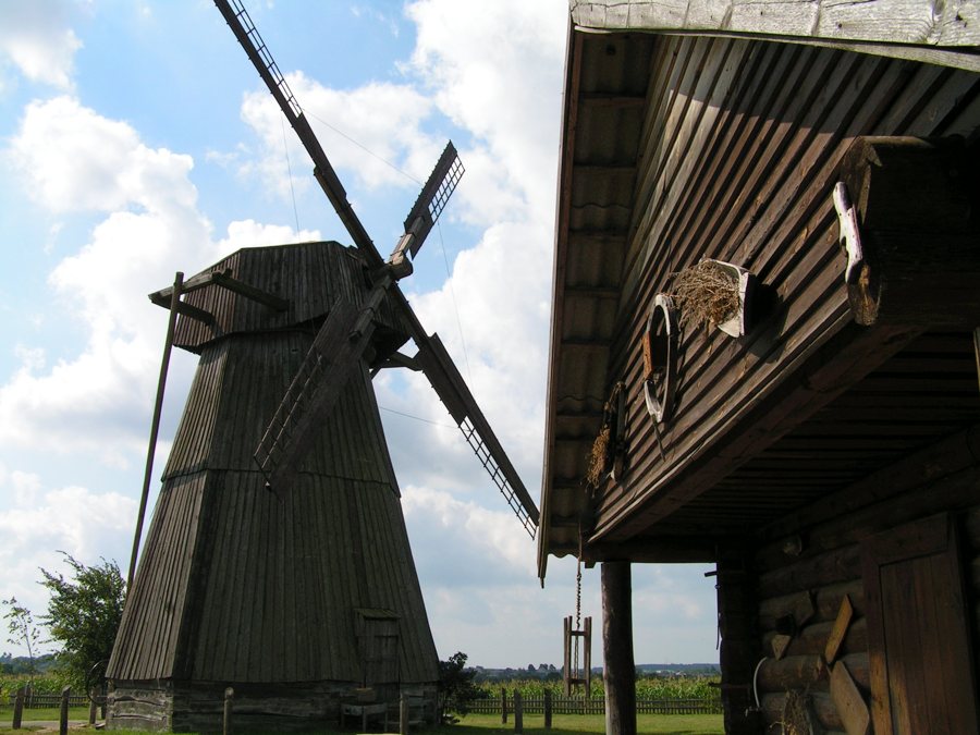 Historic wooden windmill and traditional timber building at the Dudutki open-air museum in Belarus