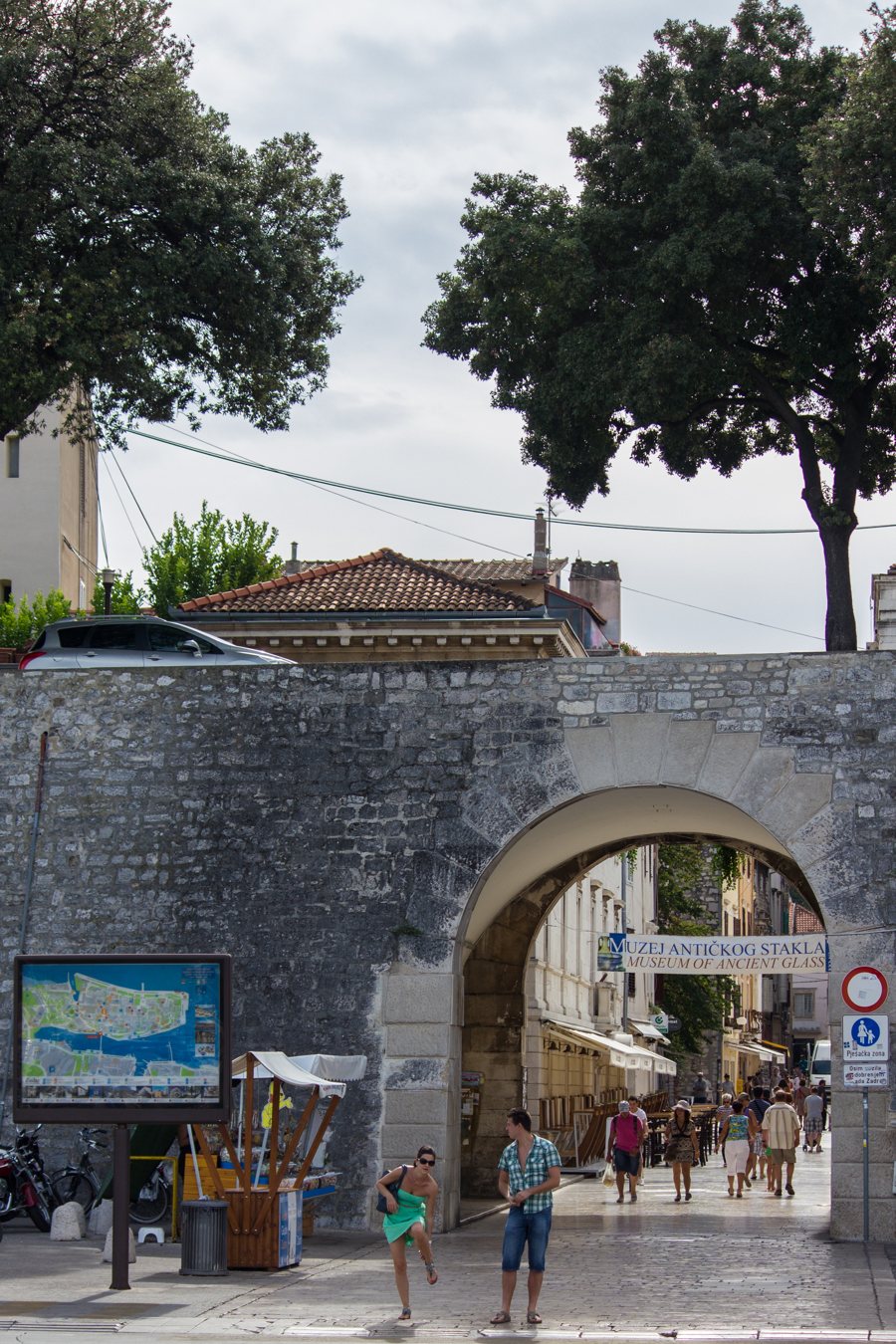 Stone archway leading into an old town street with pedestrians