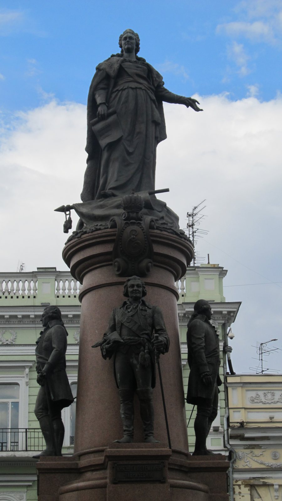 Monument with bronze figures in front of historic buildings in Odessa